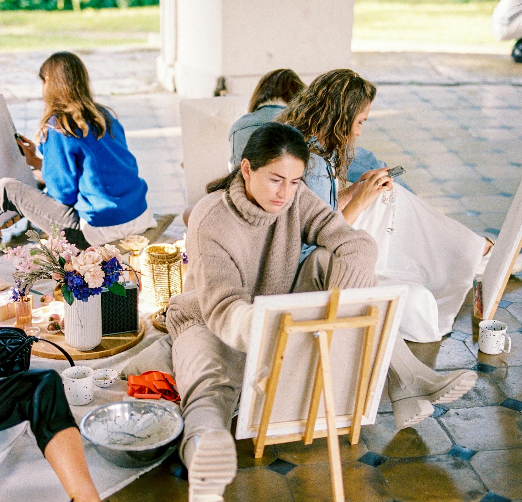 A group of women engaged in painting and creating art in an outdoor workshop.